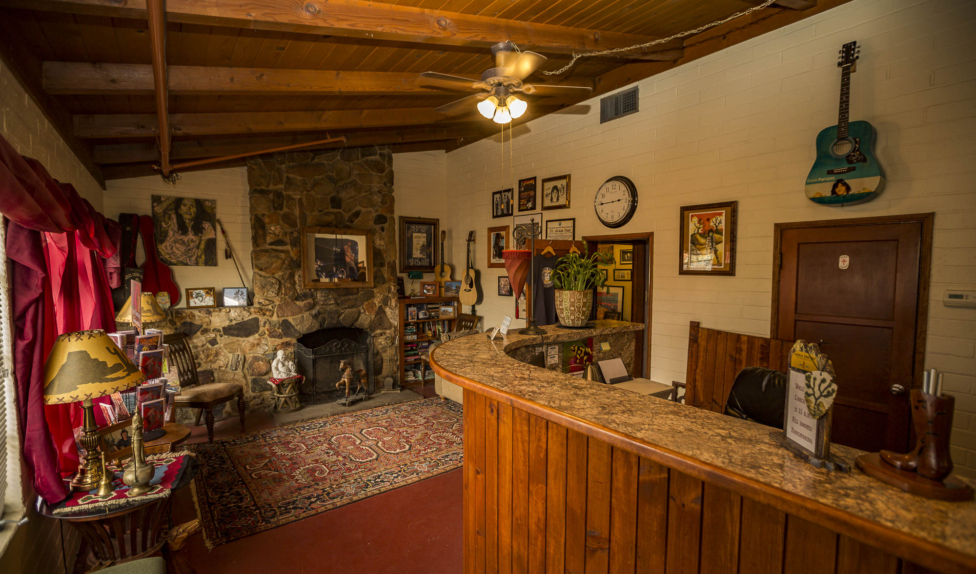The main office, there is a tall wooden desk to the right and a seating area with a stone fire place to the left.